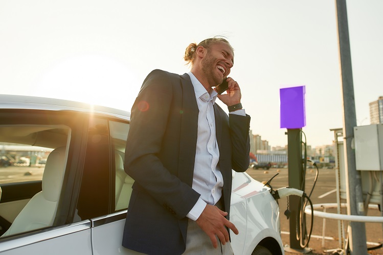 Empresário falando no telefone enquanto o carro elétrico carrega