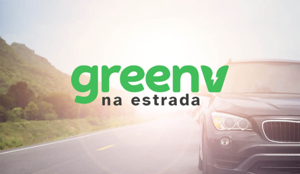 Fotografia colorida mostra um veículo preto trafegando na estrada. O texto no centro da imagem diz: GreenV na estrada.