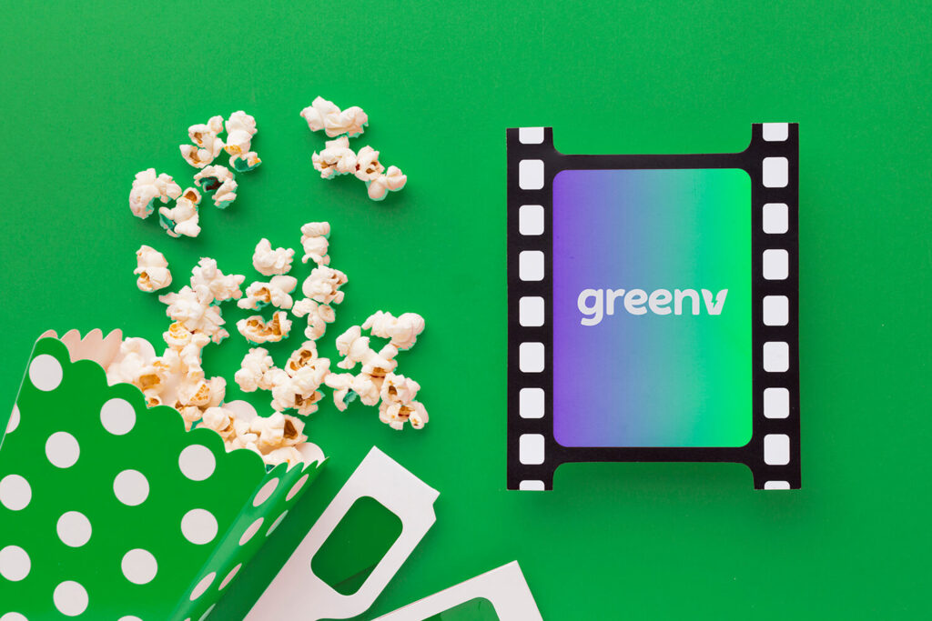 Imagens ilustrativa colorida mostra um balde de pipoca ao lado de um rolo de filme, com o logo da GreenV no meio.