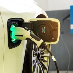 Power supply connect to electric car for add charge to the battery. Charging re technology industry transport which are the future of the Automobile with station charge on background
